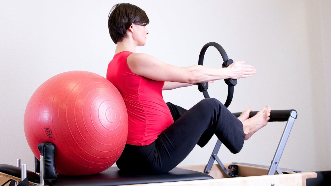 woman in red top leaning on red stability ball