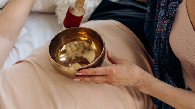 woman holding singing bowl on person s stomach