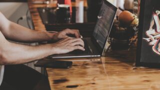 person in front of laptop on brown wooden table