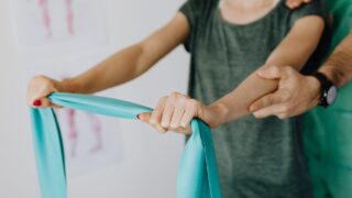 crop anonymous woman stretching elastic band near professional chiropractor